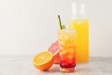 Glass of tasty Tequila Sunrise cocktail on light background