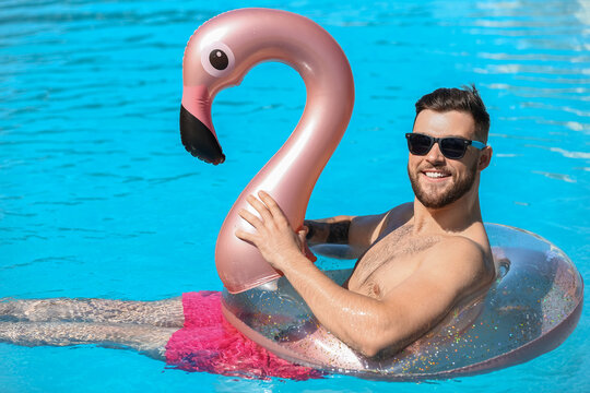 Young man with inflatable ring in swimming pool