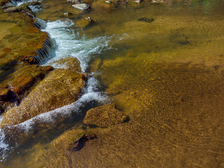 Clear water in a stream, near rocks and waterfalls with copy space. Natural shallow stream water background.