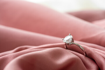 The wedding diamond ring is placed on a pink gold cloth.