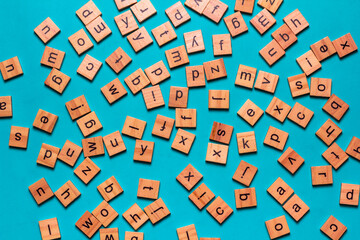English alphabet made of square wooden tiles with the English alphabet scattered on blue...