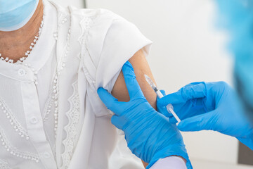 Doctors are vaccinating an elderly woman in a white shirt to build up the coronavirus or COVID-19...