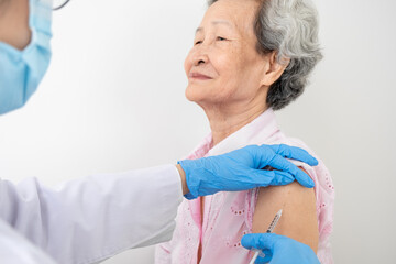 Woman doctor is vaccinating a white-robed Asian woman to protect against the coronavirus or COVID-19