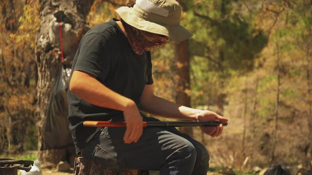 A man cocks and reloads his bb gun while hunting for leisure in a forest, USA