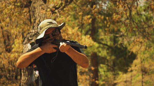 Close up of a man shooting a bb gun and reloading while shooting cans in a campground