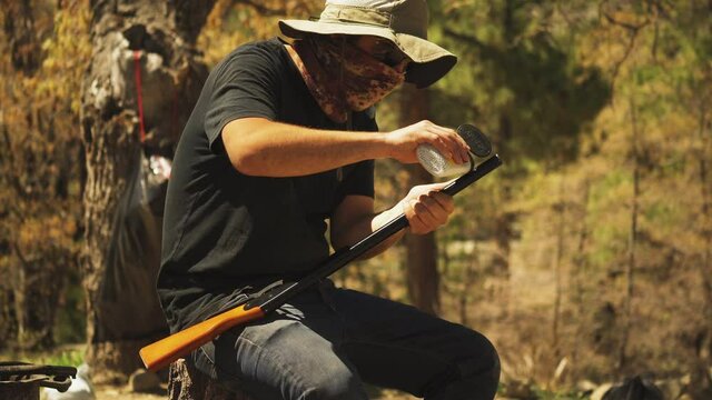 Close up of man reloading his air powered bb gun with ammo while shooting for target practice