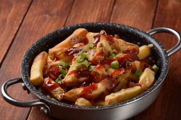 French fries with Melted Cheddar Cheese with Crispy Bacon. Poutine with cheese, bacon and green onions