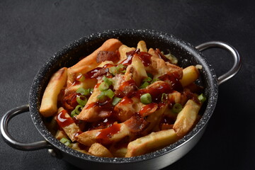 French fries with Melted Cheddar Cheese with Crispy Bacon. Poutine with cheese, bacon and green onions