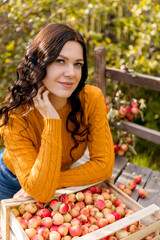 A young woman picks apples in the autumn garden