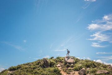 hiking man standing on the peak of a small hill. goal and sucess