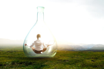 Business man doing yoga in lotus pose inside glass bottle