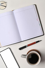Top view empty notebook, smart phone and coffee cup on white table.