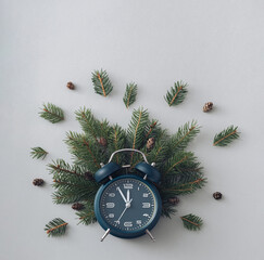Fototapeta na wymiar Alarm clock and pine branches on a gray background concept of winter holidays and vacations Flat lay