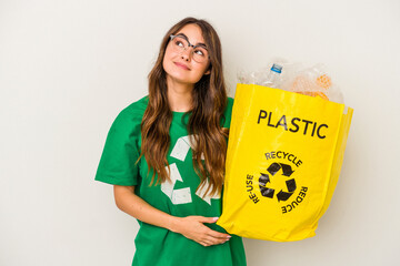 Young caucasian woman recycling a full of plastic isolated on white background  dreaming of...
