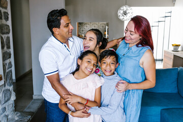 Portrait of happy hispanic family and teenage daughter with cerebral palsy at home in Latin America...