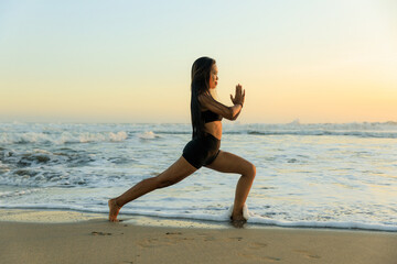 Fototapeta na wymiar Yoga on the beach. Ashta chandrasana. High lunge pose lengthens the sides of the body, opens hips. Hands in namaste mudra. Healthy lifestyle. Yoga retreat. Copy space. Seminyak beach, Bali