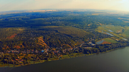 Photo from a drone of a beautiful summer landscape over the river. Beautiful summer landscape with a wide river and green coastline. Aerial photography of the suburban landscape.
