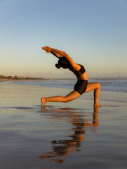 Sunset beach yoga. Anjaneyasana, Low Lunge Pose. Crescent Moon Pose. Lunging back bending asana. Supporting muscle. Flexible spine. Yoga retreat. Water reflection. Seminyak beach, Bali