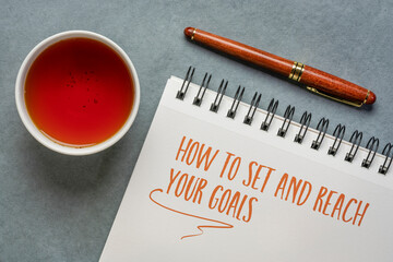 how to set and reach your goals, handwriting in a spiral notebook with a cup of tea, business and personal development concept