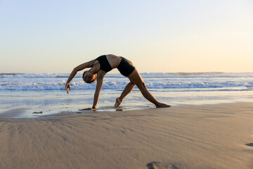 Yoga retreat. Beautiful asana. Slim woman practicing yoga on the beach. Stretching exercise. Flexible body. Copy space. Horizontal layout. Seminyak beach, Bali