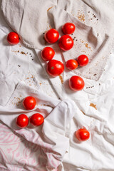 Naklejka na ściany i meble Red tomatoes on crumpled light fabric, scattered mustard and pepper.
