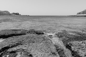 Horizontal view of the ground's geological formation on the ocean's side in black and white