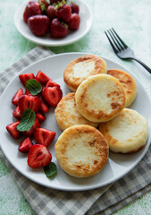 Naklejka na ściany i meble Cottage cheese pancakes, ricotta fritters on ceramic plate with fresh strawberry.