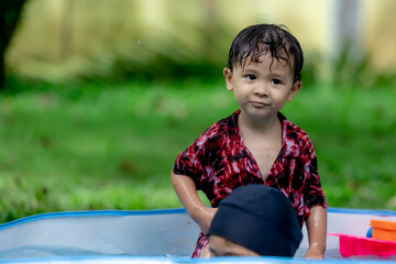 Asian boy and girl playing water in the garden