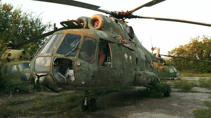 Abandoned MI-8 helicopter with broken flight deck without door at standoff soviet aerodrome at orange sunset light in summer