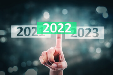 Hands press 2022 numbers with blurred sparkling