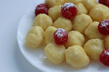 Homemade cheesecakes with balls of cottage cheese with fresh raspberries on a light background with powdered sugar