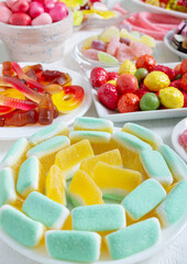 Multicolored yummy gummy candies on plates. Vertical view