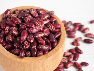 red beans in a wooden bowl on a white wooden table, copy space