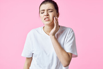 woman in white t-shirt holding her neck pain problems pink background