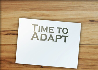 text Time to Adapt page, paper signs of dollar on wood table. Business concept