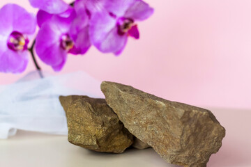 A gentle background for the presentation of cosmetic products. Stones and orchid flowers. Stylish appearance, layout, personality. Banner, a place for the text.