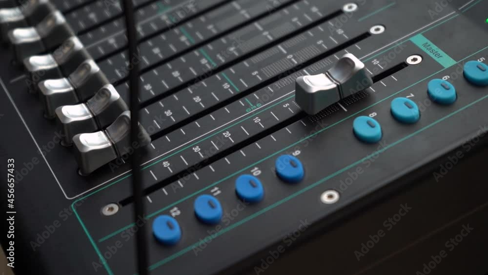 Poster close up of channel faders and buttons of a digital audio mixer.