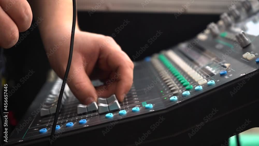Poster hand of an audio engineer adjusting the fader of a sound mixer. - close up