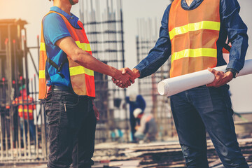 Architect and engineer construction workers shaking hands while working at outdoors construction...