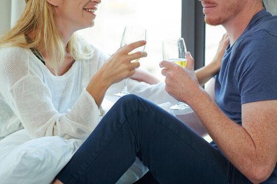 Cropped image of young man and women drinking champagne and discussing news when sitting on window sill