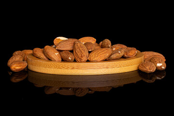 Lot of whole almond on bamboo coaster on black glass