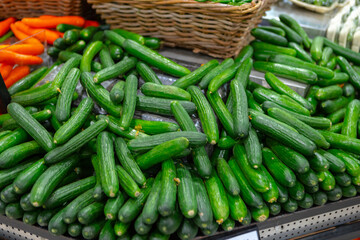 Pile of fresh cucumbers on counter in supermarket