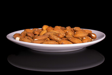 Lot of whole almond on white ceramic plate on black glass