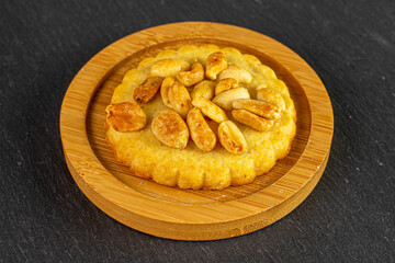 One whole delicious cookie with peanuts on bamboo coaster on grey stone