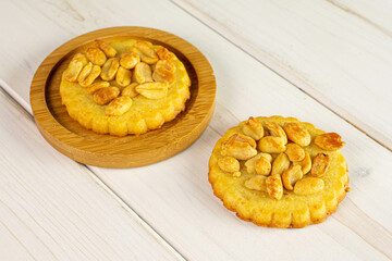 Group of two whole delicious cookie with peanuts on bamboo coaster on white wood
