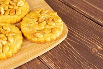 Group of three whole delicious cookie with peanuts on bamboo cutting board on brown wood