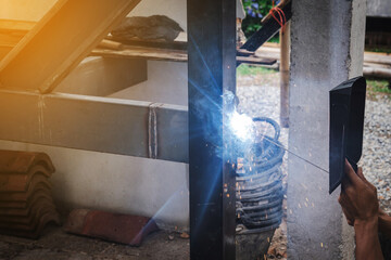 Man welder doing a metal staircase structure in a residential building using a welding machine.