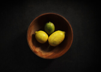 A bowl of lemons on a black background