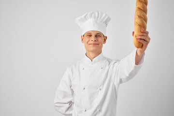 a man in a chef's uniform with a loaf in his hands fresh food work light background