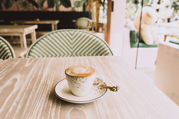 white cup of hot cappuccino on wooden light table background.